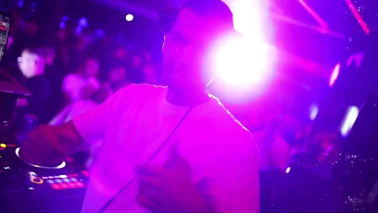 DJ za pultom tokom BRIDŽOVANJE žurke, ljubičasto osvetljenje